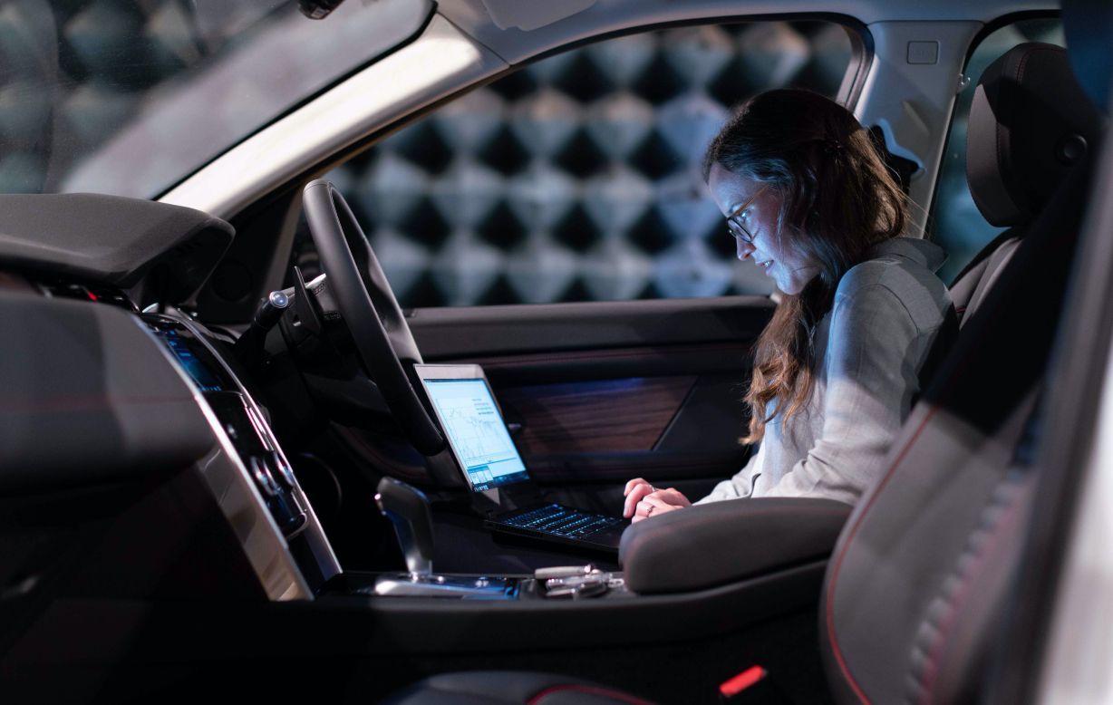 A girl working on laptop inside her car.